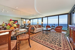 Relax in a spacious living area with a central seating area, dining table, and expansive ocean views.