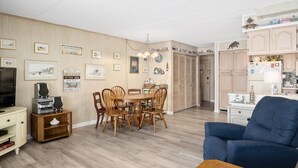 A living room with a dining table, chairs, a blue sofa, and a TV. - 3 br / 2 bath for 10, direct beach/ocean and boardwalk views~ (Ocean City)