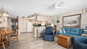 A spacious living area with a dining table, blue sofa, and a ceiling fan. - 3 br / 2 bath for 10, direct beach/ocean and boardwalk views~ (Ocean City)