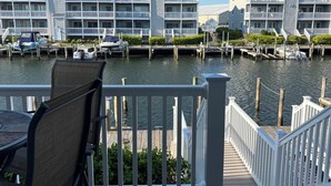 A waterfront property with a dock, boats, and a view of a multi-story building with balconies.