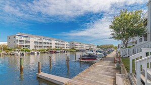 A marina with docked boats, a wooden pier, and a row of apartment buildings.