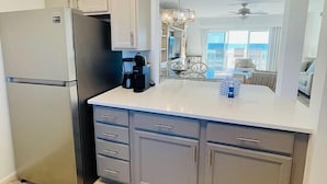 Una cocina equipada con refrigerador, cafetera y un comedor con candelabro.