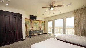 Une chambre d’hôtel avec deux lits, un ventilateur de plafond, une grande fenêtre avec vue et un balcon.