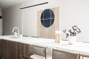 A modern kitchen with a central island, a pendant light, and a wall-mounted artwork. - Denver Skyline Views | Walk to Empower Field (Denver)