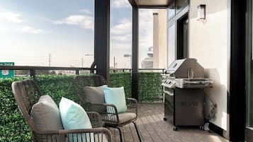A balcony with wicker chairs and a grill.