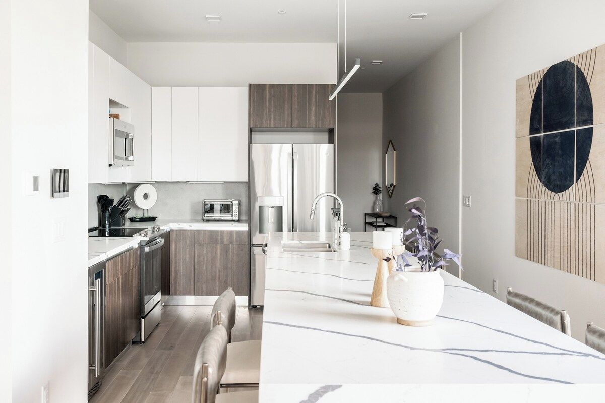 A modern kitchen with a central island, stainless steel appliances, and a dining area with a large table.