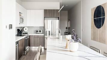 A modern kitchen with a central island, stainless steel appliances, and a dining area with a large table.