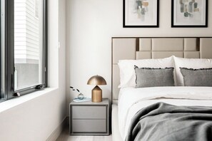 A bedroom with a bed, bedside table, lamp, and artwork on the wall. - Denver Skyline Views | Walk to Empower Field (Denver)