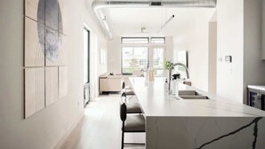 A modern kitchen with a marble countertop, a built-in oven, and a large window providing natural light. - Denver Skyline Views | Walk to Empower Field (Denver)