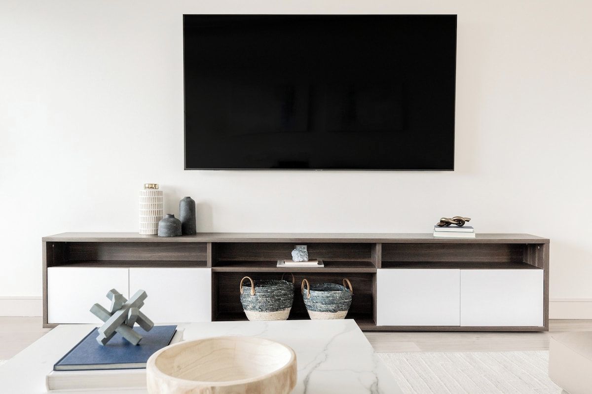 A modern living room with a flat-screen TV mounted on the wall, a wooden coffee table, and a minimalist console table with decorative items.