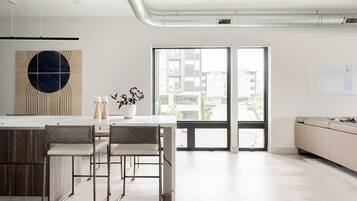 A modern kitchen with a central island, bar stools, and a view through a glass door to an outdoor balcony.