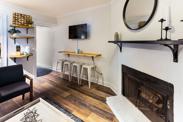Una sala de estar con chimenea, estanterías de madera, un televisor y un sofá.