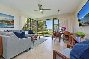 Relax in this stylish living room with a sofa, coffee table, and TV, offering a view of the lush garden.