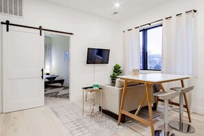 A modern living room with a sofa, a dining table, and a TV.
