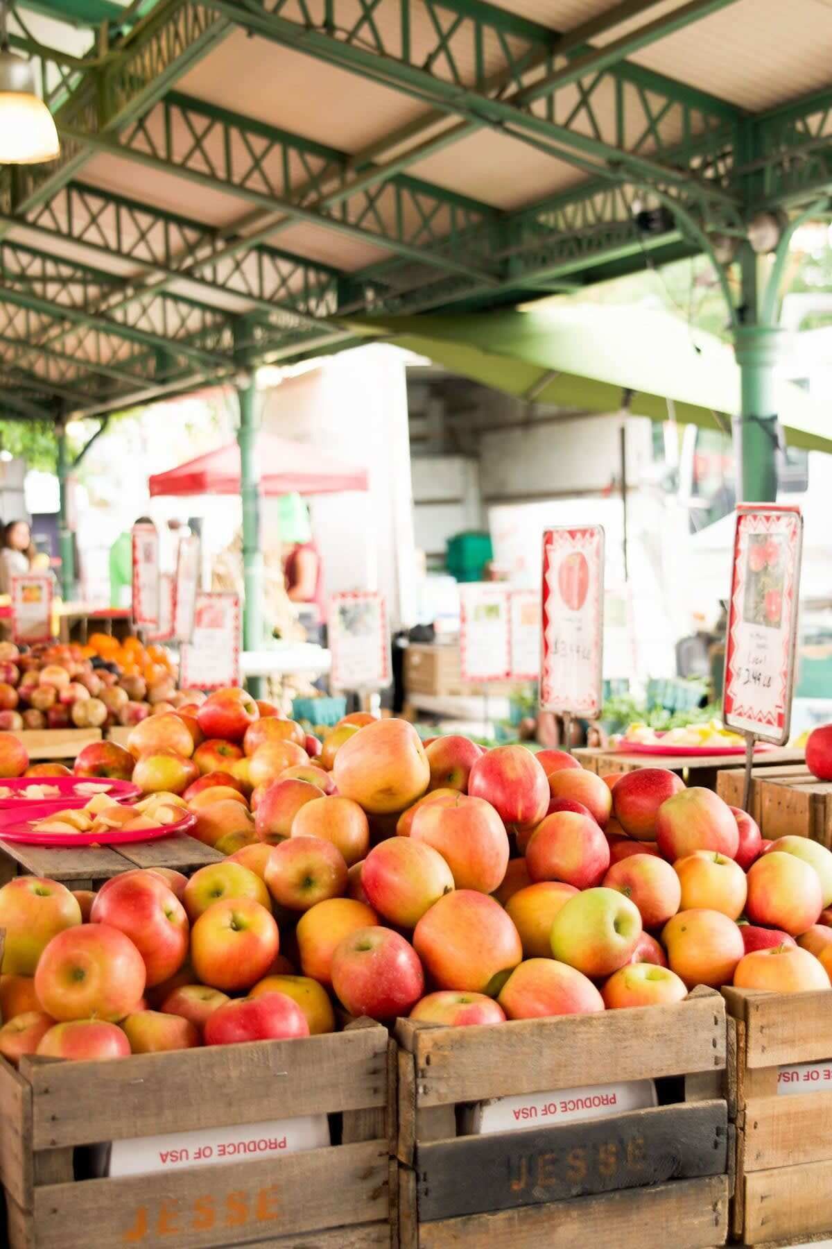 A market stall with crates of apples and oranges, wooden crates labeled 'Jesse's Produce of USA'.