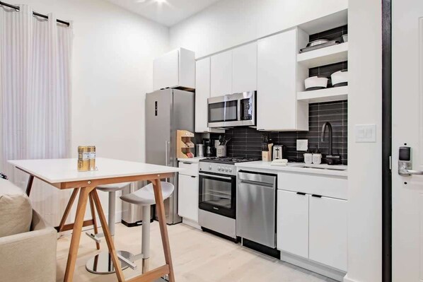 A compact kitchen with white cabinets, a microwave, stove, and a dishwasher. - Eastern Market & METRO Accessible, Modern Charm, Walk Everywhere! (Washington)