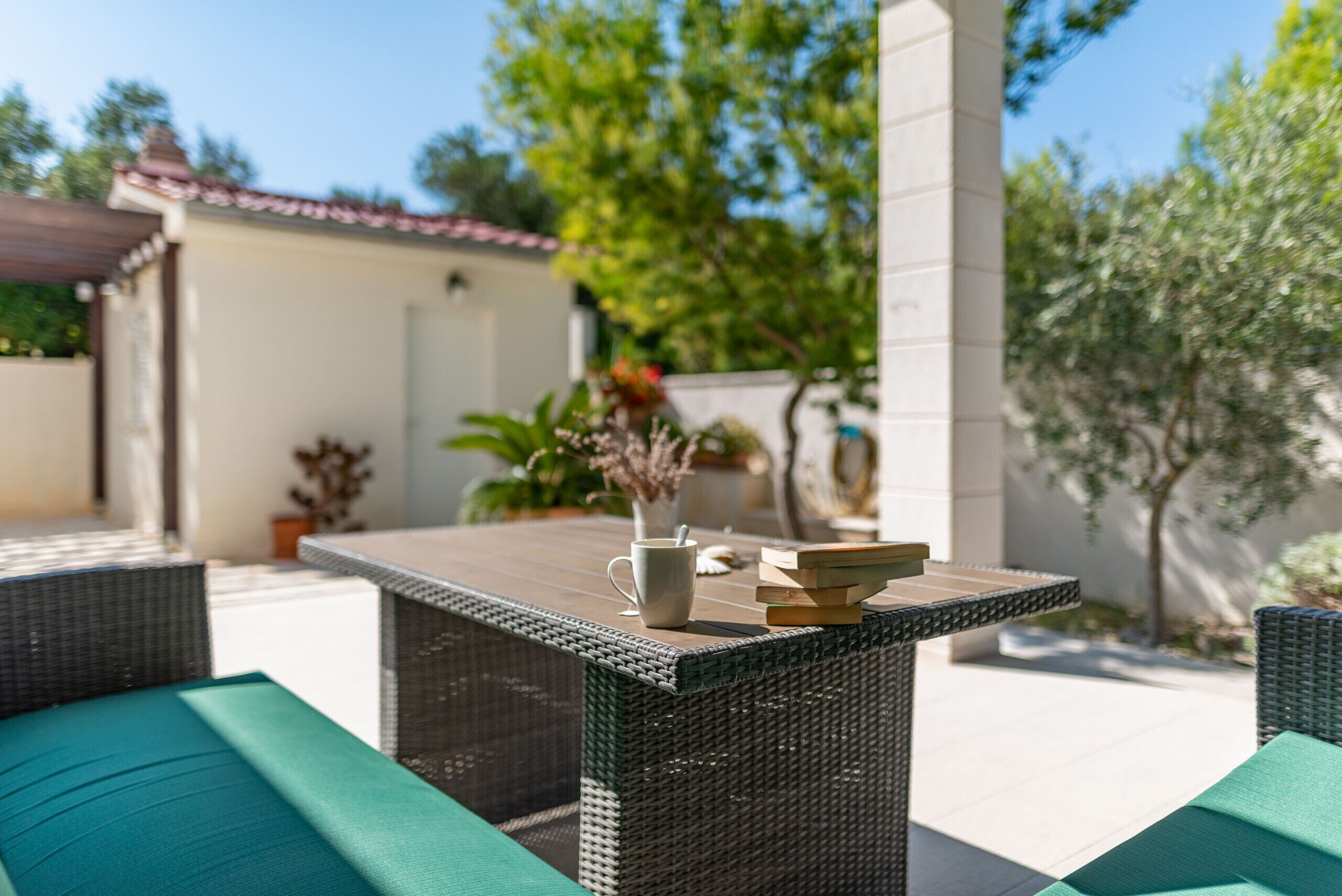 An outdoor patio area with wicker furniture, a table, and a potted plant.