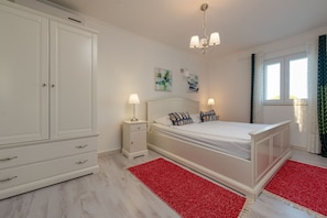 A bedroom with a bed, nightstands, a wardrobe, and artwork on the wall.