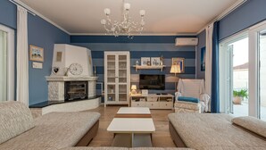 Ein Wohnzimmer mit Kamin, einer Couch, einem Fernseher und einer Chandelier.