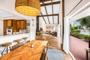 A spacious kitchen with wooden cabinets, a large dining table, and a hanging light fixture.