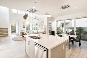 A modern kitchen with a central island, built-in appliances, and large windows.