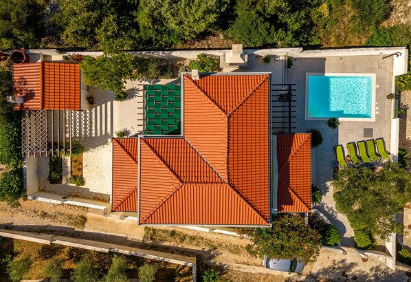 Vista aérea de un resort con piscina, varias áreas techadas y un patio con sillas de descanso.