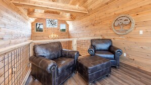 Un intérieur chaleureux avec des éléments en bois, notamment deux fauteuils en cuir, un plafond en bois et une décoration murale représentant un arbre.