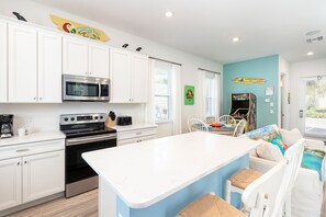 Une cuisine moderne avec des meubles blancs, un îlot central et un coin repas comprenant une table et des chaises.