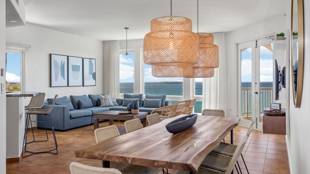 A spacious living area with a wooden dining table, wicker chairs, and a blue sofa.