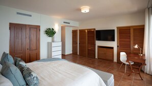 A bedroom with a bed, a desk, a chair, a TV, and wooden closets.