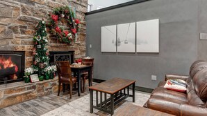 A cozy living room with a stone fireplace, a Christmas tree, and a chessboard.