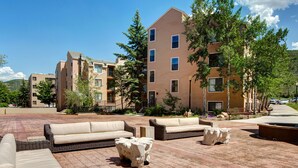 A courtyard with outdoor seating, a fire pit, and a building with multiple floors and balconies.