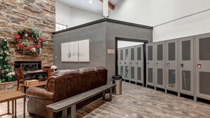 A lobby with a stone wall, a fireplace, a bench, a Christmas tree, and lockers.