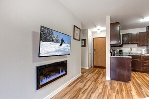 A modern kitchen with wooden cabinets, a built-in island, and a flat-screen TV mounted on the wall.