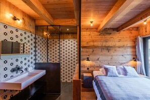 Interno di una baita in legno con bagno, un letto e una zona doccia.