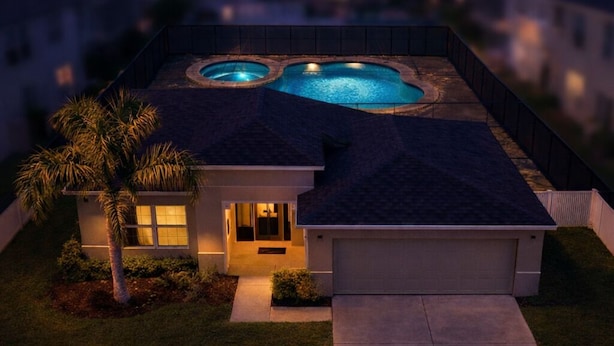 Um imóvel residencial com piscina, varanda coberta e entrada bem iluminada.