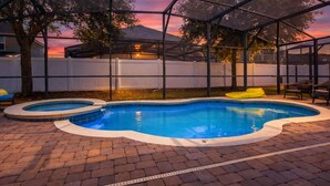 Um quintal com piscina, varanda coberta e vista para o pôr do sol.