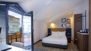 Et moderne hotelværelse med seng, skrivebord, stol, rundt bord og udsigt ud