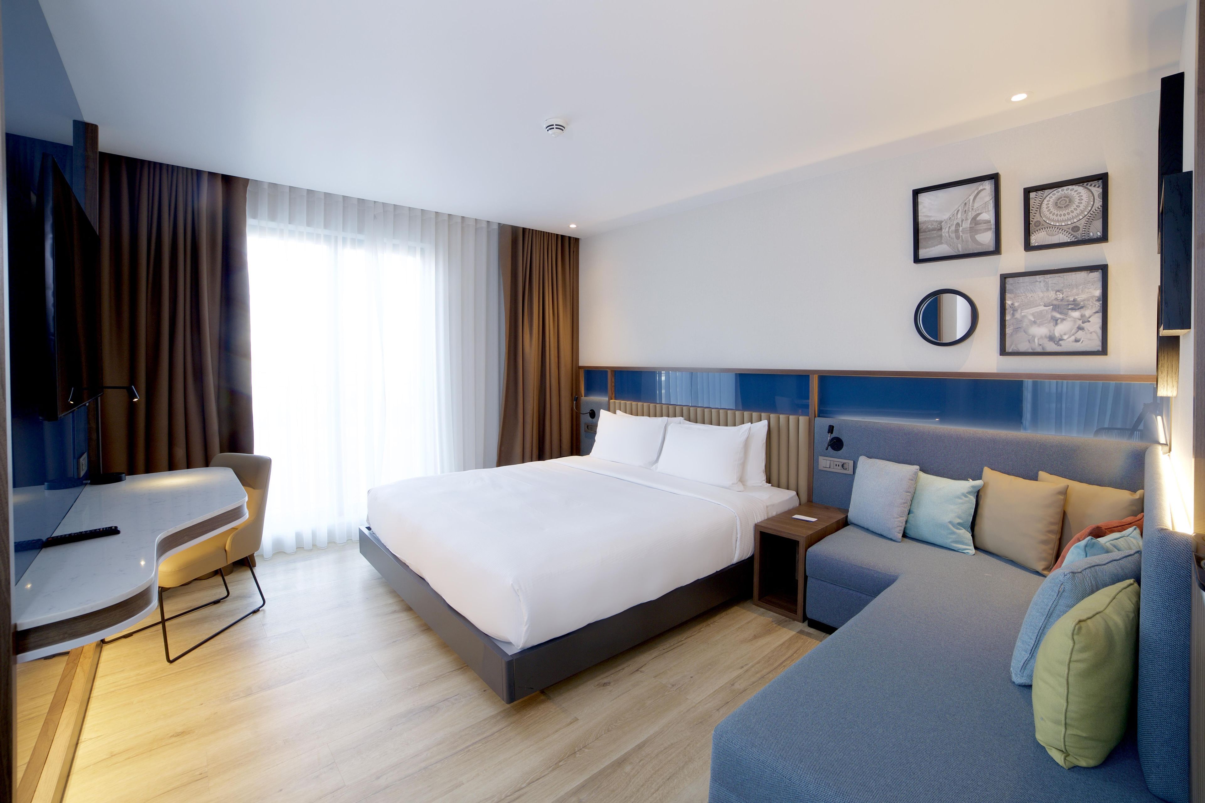 Ein modernes Hotelzimmer mit einem großen Bett, einem Schreibtisch und einer Couch.