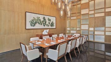 Une salle de conférence avec une longue table, des chaises, une œuvre d’art encadrée et un mur en bois doté d’une cloison en verre.