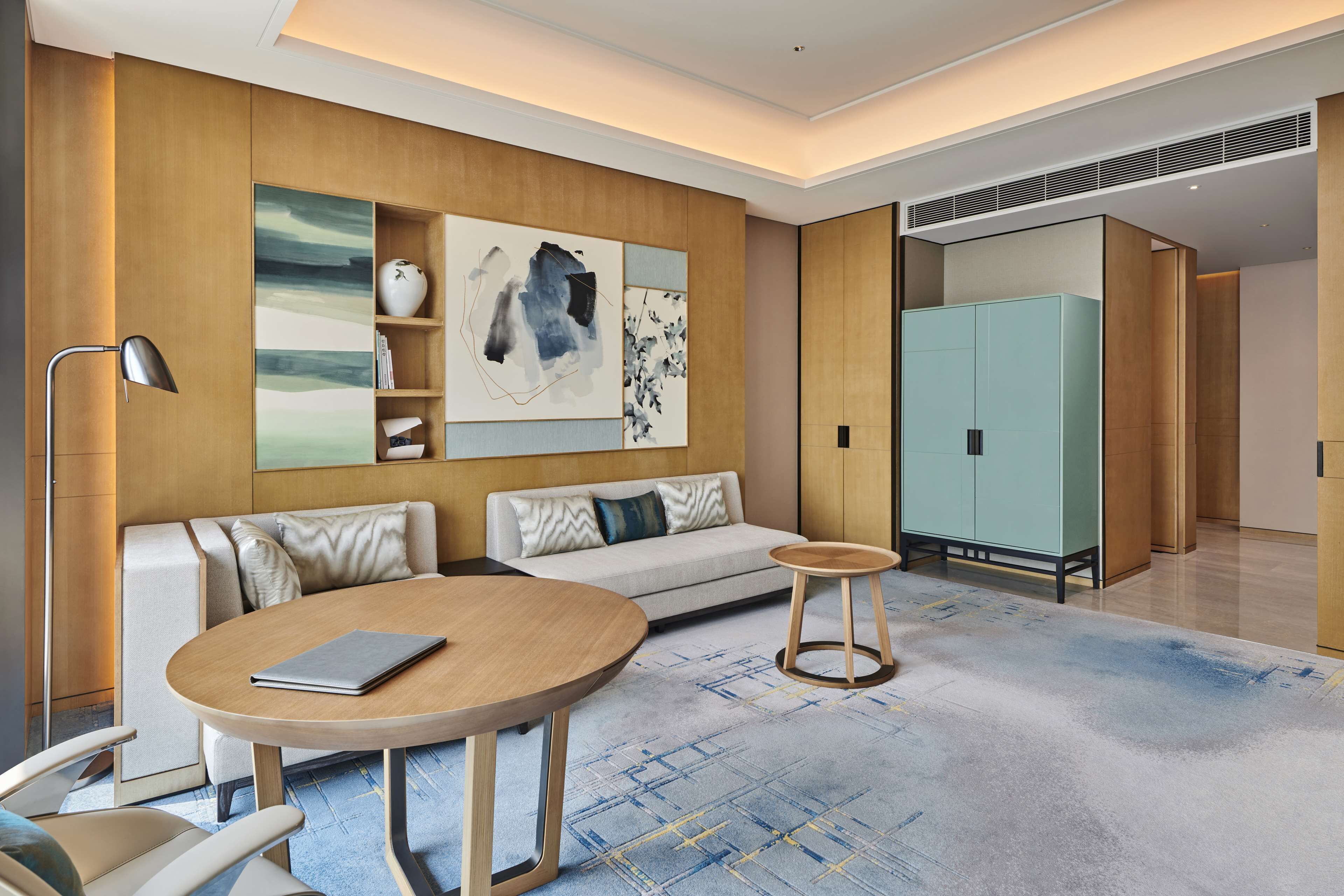 A modern living room with a sofa, two round tables, a floor lamp, and artwork on the wall.