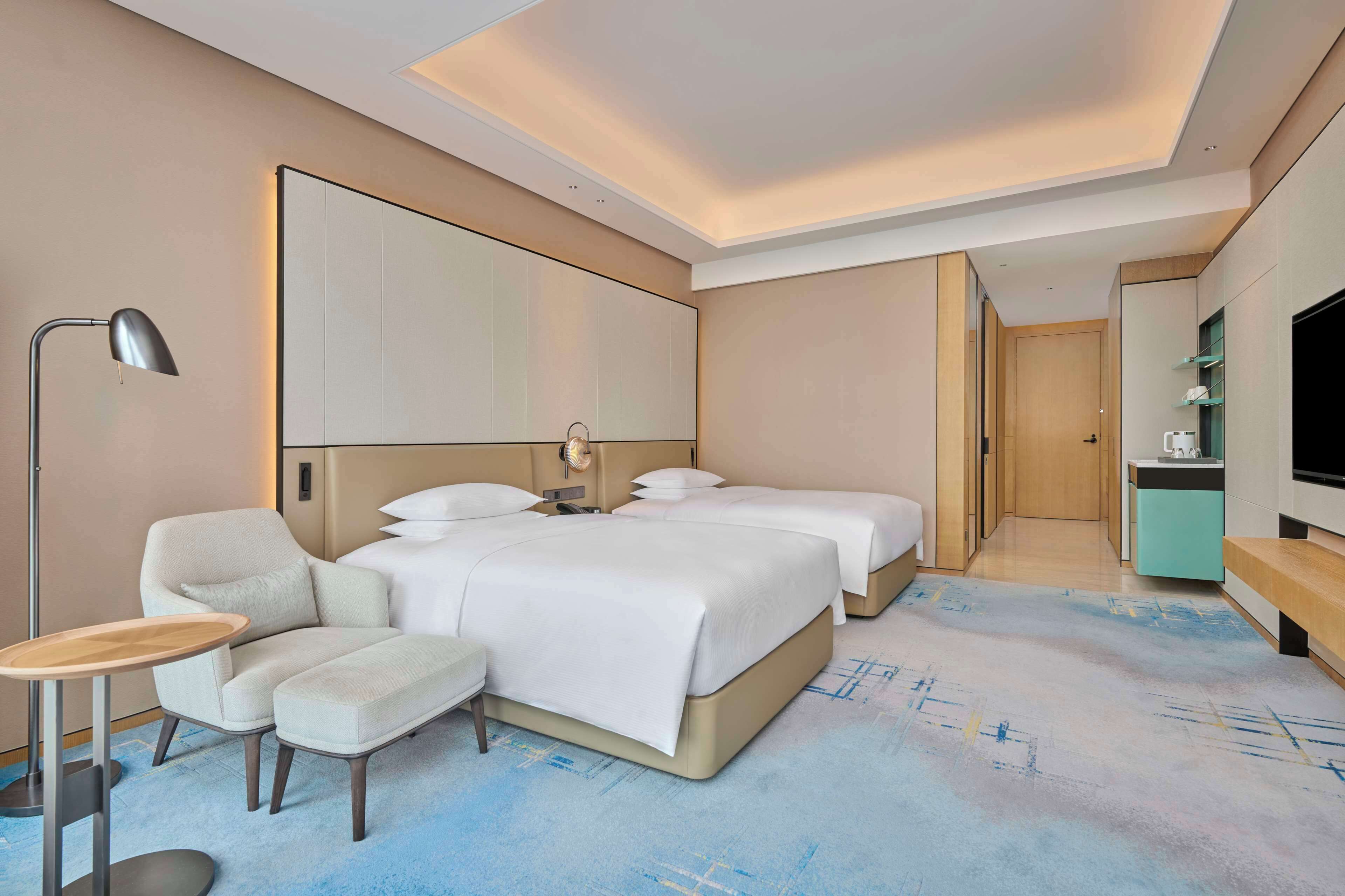 Hotelkamer met een groot bed, een bureau, een stoel, een televisie en een kitchenette.