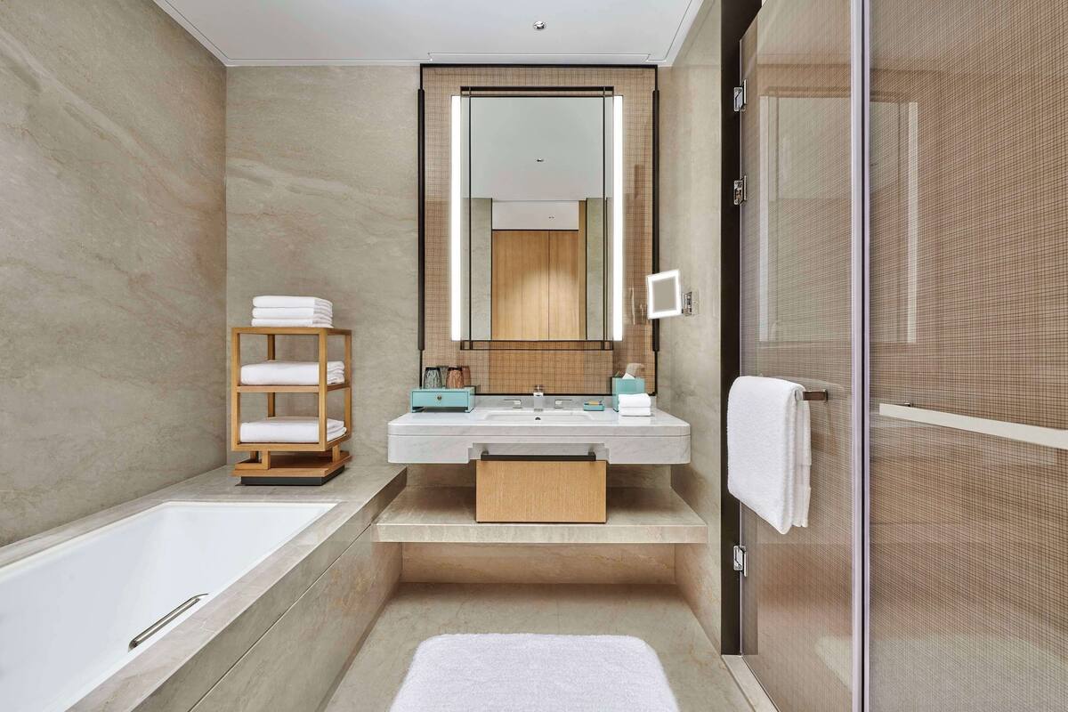 Ein modernes Badezimmer mit Badewanne, Waschtisch mit Spiegel und einem Handtuchregal.