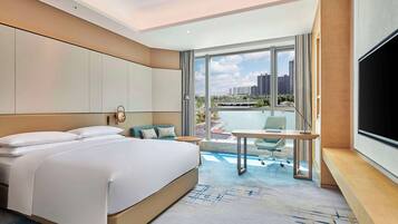 A modern hotel room with a large bed, a desk, and a TV.