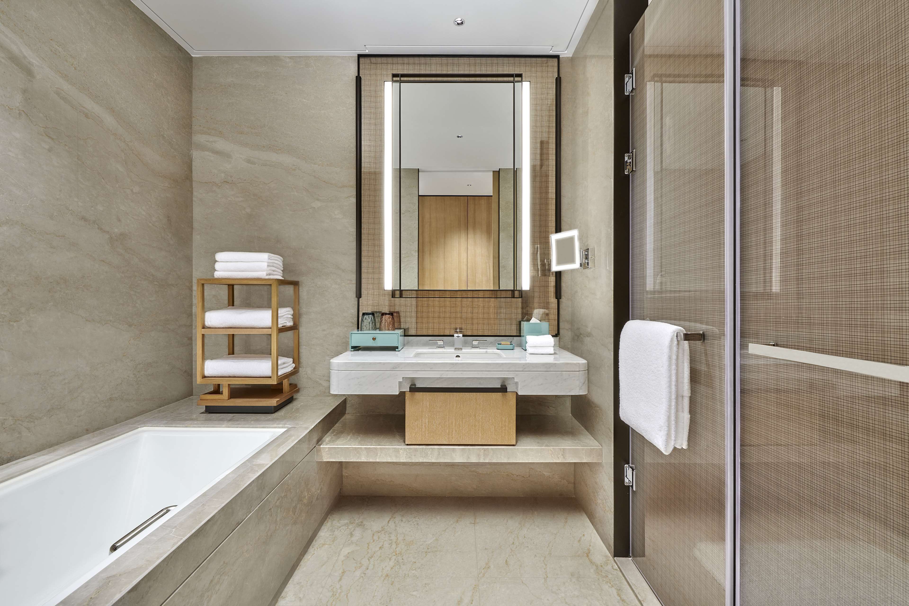 A modern bathroom with a bathtub, a vanity with a mirror, and a towel rack.