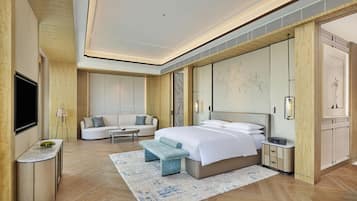 A modern bedroom with a large bed, a sofa, a TV, and a desk.