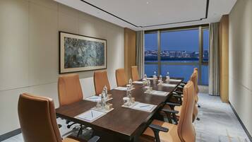 A conference room with a long table, leather chairs, and a city view through large windows.