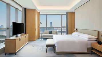 Ein modernes Hotelzimmer mit einem großen Bett, einem Fernseher auf einer Holzkommode, einem kleinen Tisch und einer Couch.