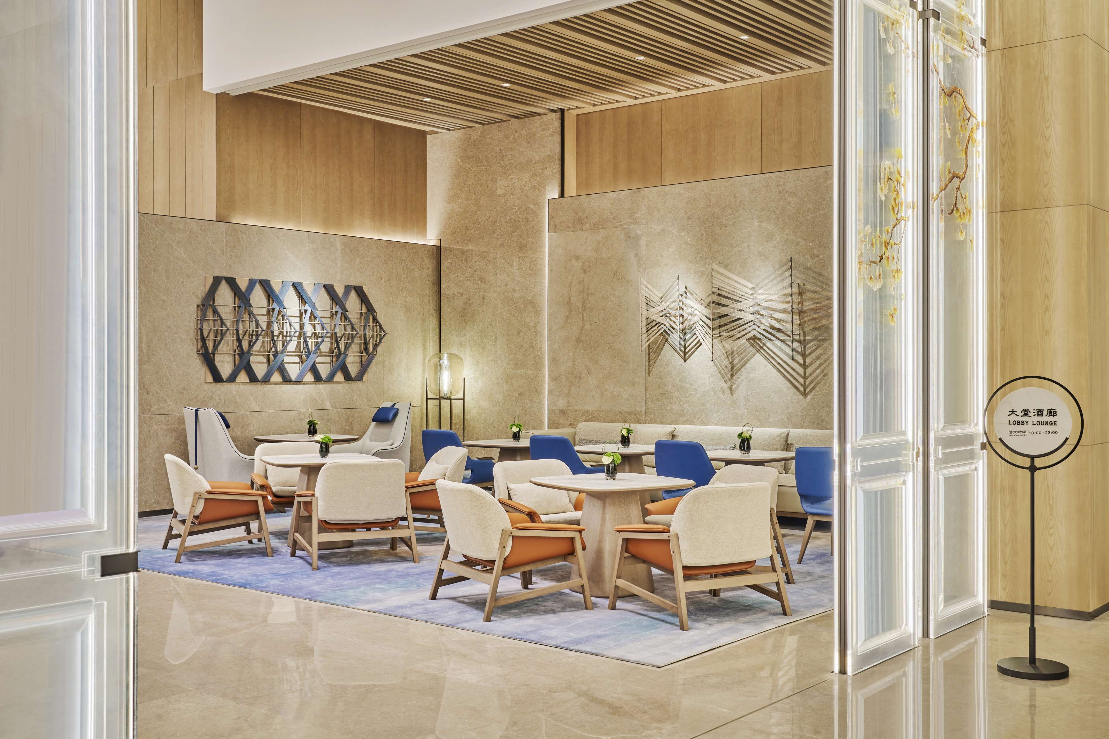 A modern lobby with a seating area, decorative wall art, and a sign indicating the lobby lounge.