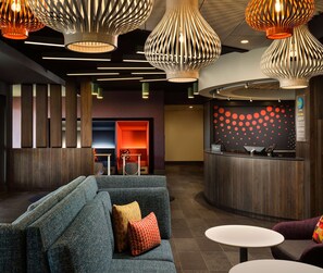 Un moderno vestíbulo de hotel con mostrador de recepción, zona de estar e iluminación distintiva.